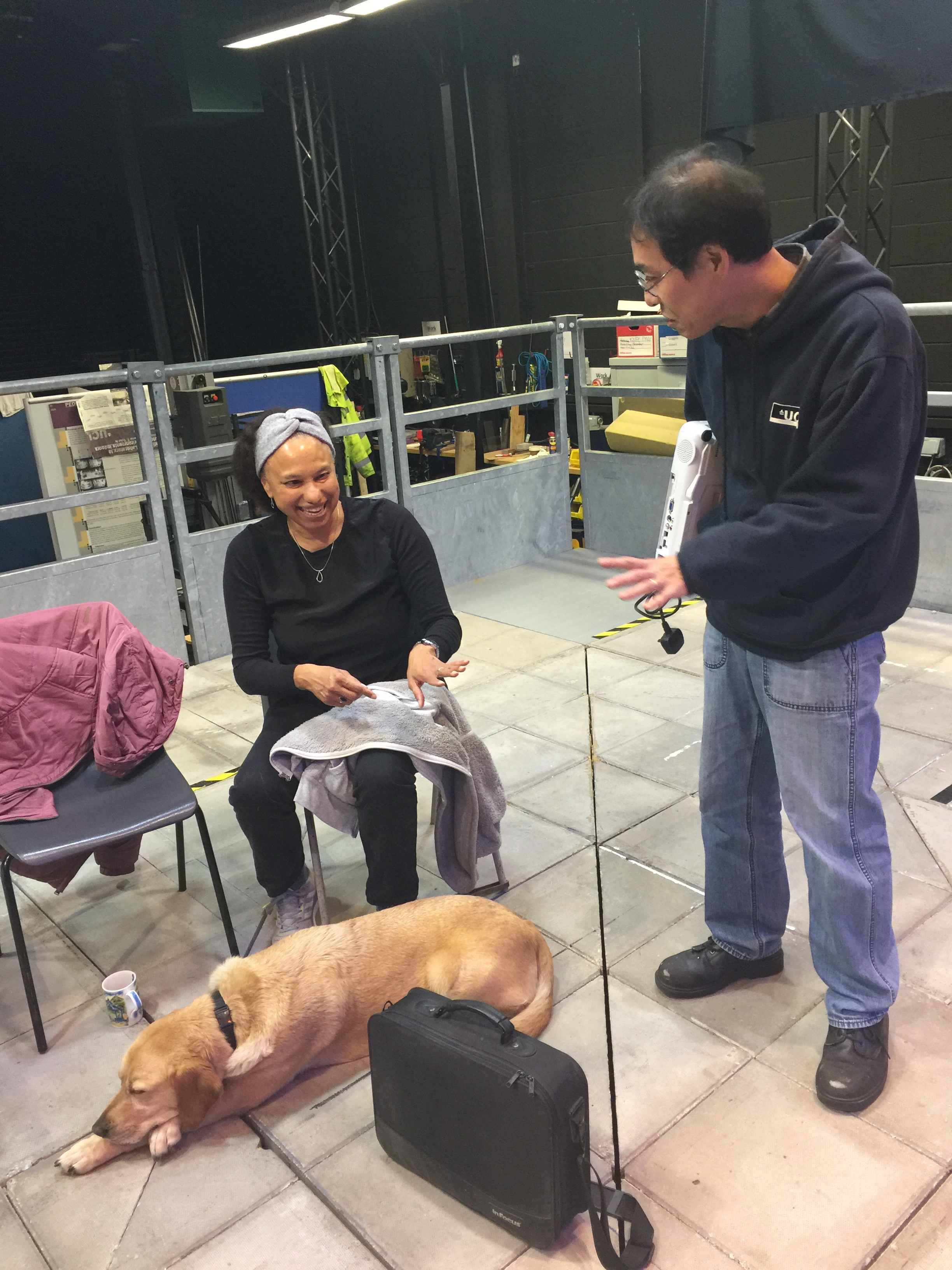 PAMELA technician Tatsuto Suzuki offers a projector to Maria, sitting on platform laughing