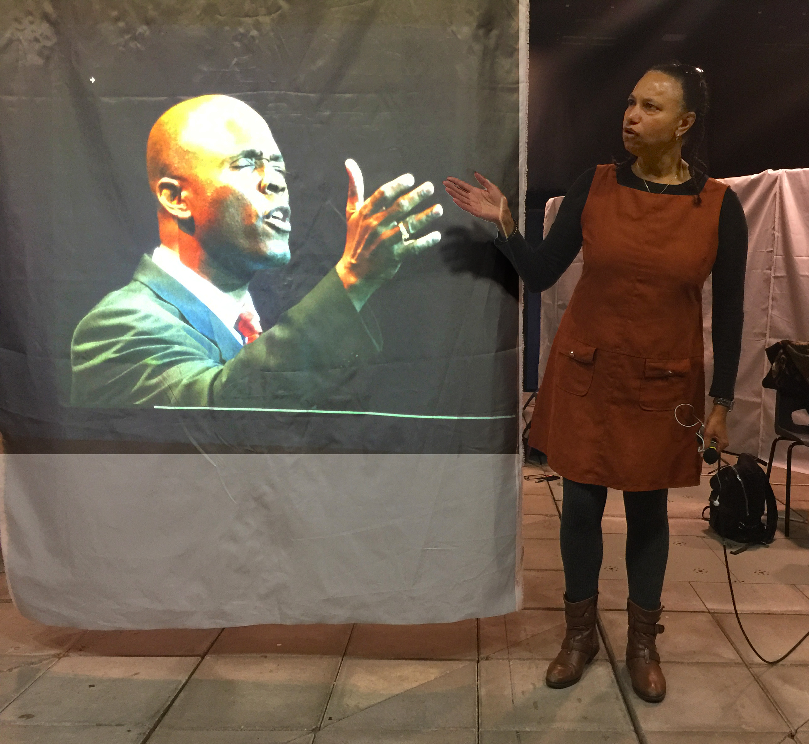 Mock up of Lynn Manning on Screen and Maria standing next to him on stage both gesticulating