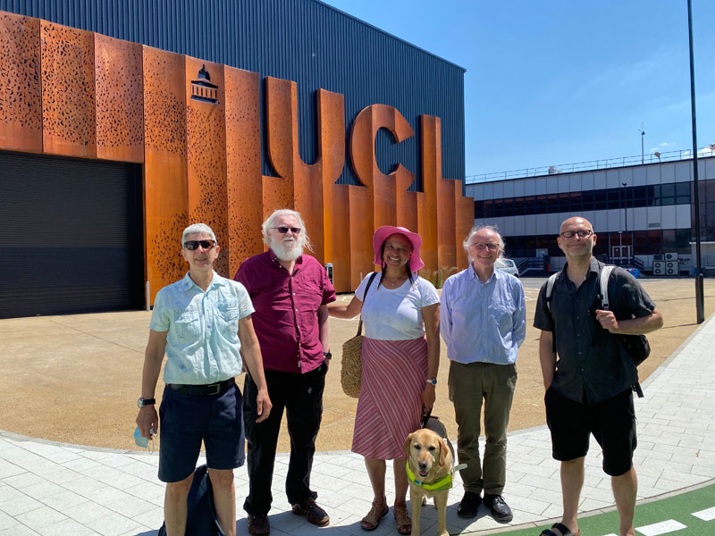 Team outside corner of PEARL building  against blue sky – From left to right, Crin, Terry, Maria +  Bella guide dog, Nick Tyler and Nic  Sandiland wearing a rucksack. 